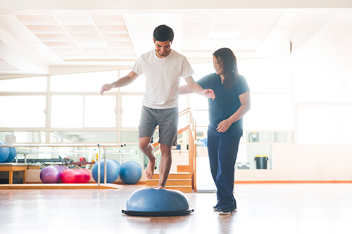 man standing on ball with one leg